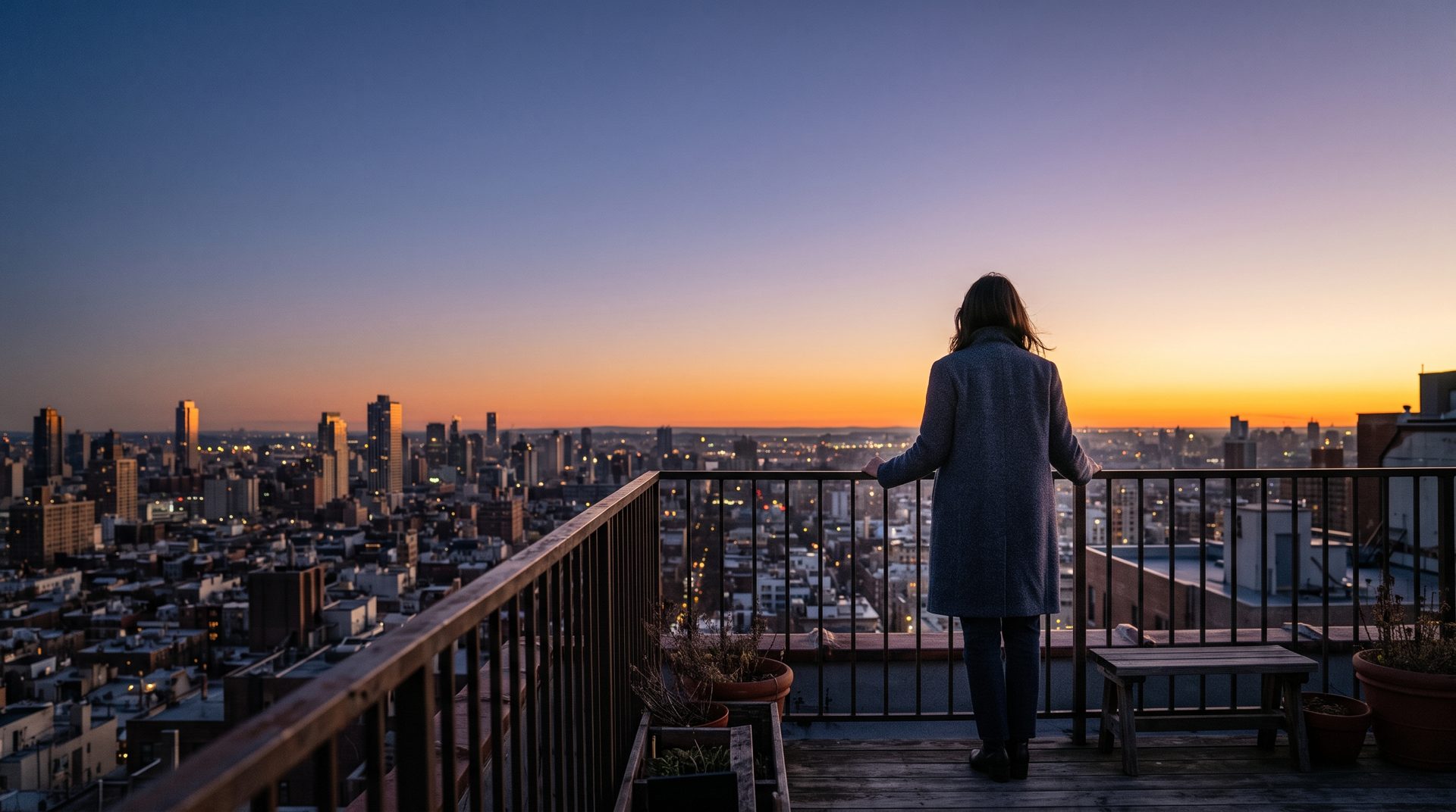 A woman on a rooftop at dawn, looking out over the city toward a glowing horizon